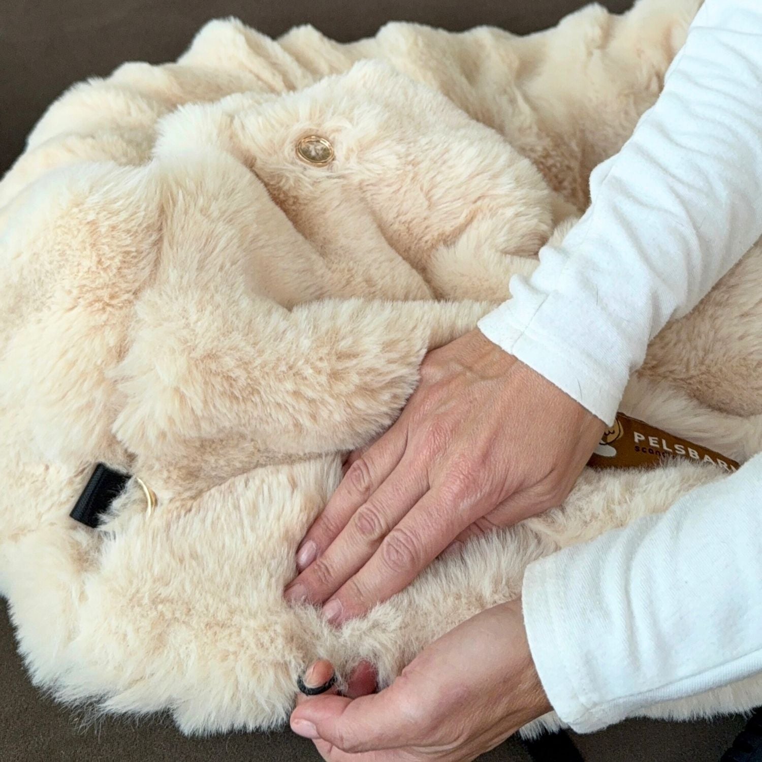 The Pelsbarn Luxurious Cozy Car Bed being folded, showing the faux fur and the strap fitting